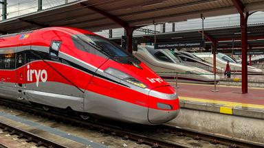 Man sieht einen roten Hochgeschwindigkeitszug auf den Gleisen