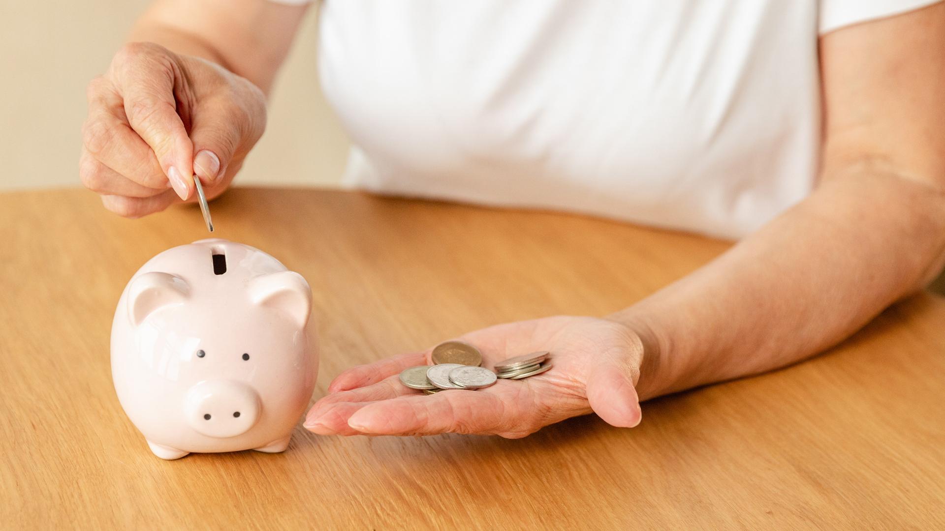 Eine Frau wirft Münzen in ein Sparschwein (Symbolbild Konsumklima).