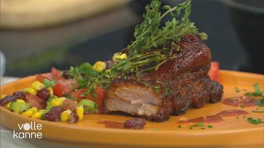 Spareribs mit Barbecue-Sauce und einem Mais-Bohnen-Salat auf einem Teller serviert.