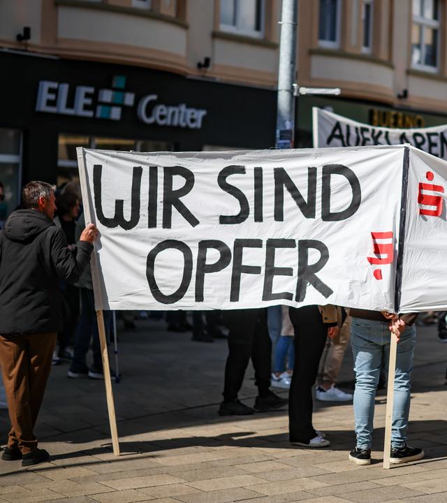 Teilnehmer einer Protestkundgebung demonstrieren gegen das als intransparent empfundene Verhalten der Sparkasse Gelsenkirchen.