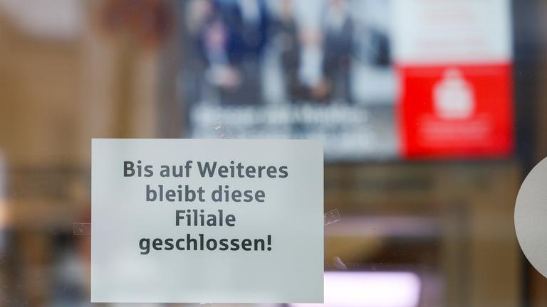Nordrhein-Westfalen, Gelsenkirchen: Ein Hinweiszettel zur weiterhin bestehenden Schließung hängt an der Glasscheibe des Vorraums der Sparkassenfiliale, im Inneren ein Monitor mit dem Sparkassen-Logo.