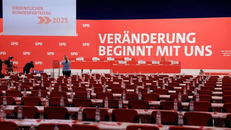 Die Halle, in der der SPD-Parteitag stattfindet. Reihen roter Stühle stehen vor einer Bühne. Auf deren Wand ist zu lesen: Veränderung beginnt mit uns. 