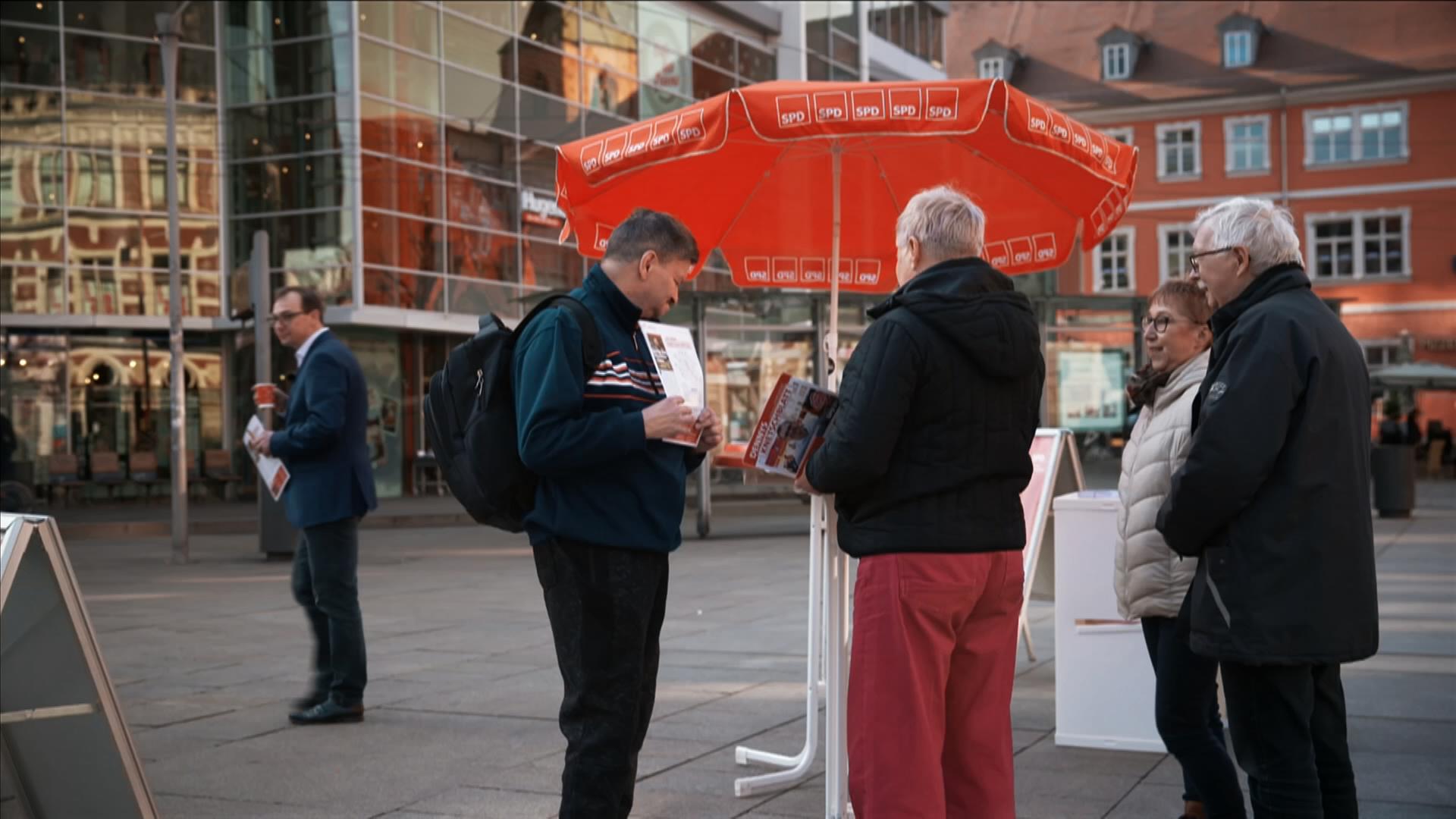 SPD-Stand mit rotem Schirm auf einem Marktplatz