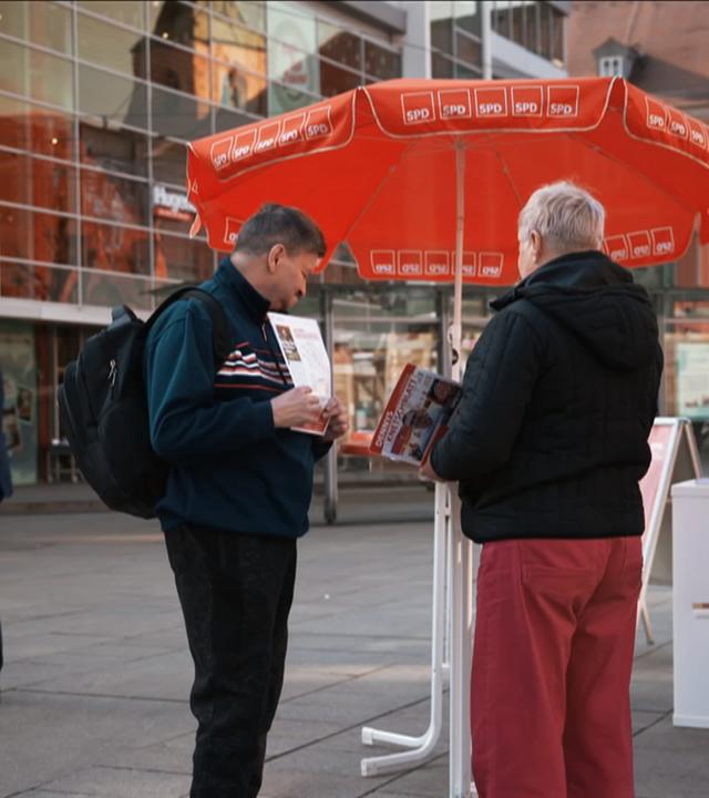 SPD-Stand mit rotem Schirm auf einem Marktplatz