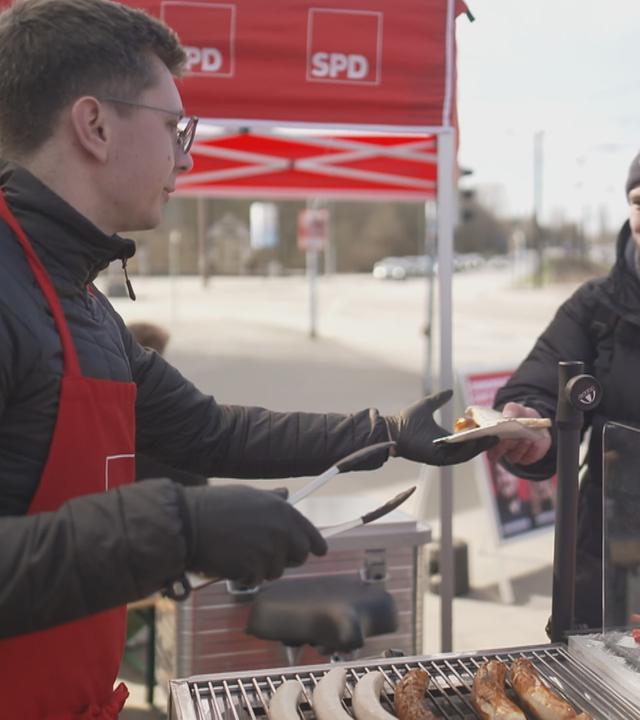 SPD-Wahlkmapfstand, bei dem Bratwurst ausgegeben wird