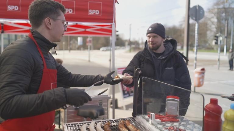 SPD-Wahlkmapfstand, bei dem Bratwurst ausgegeben wird