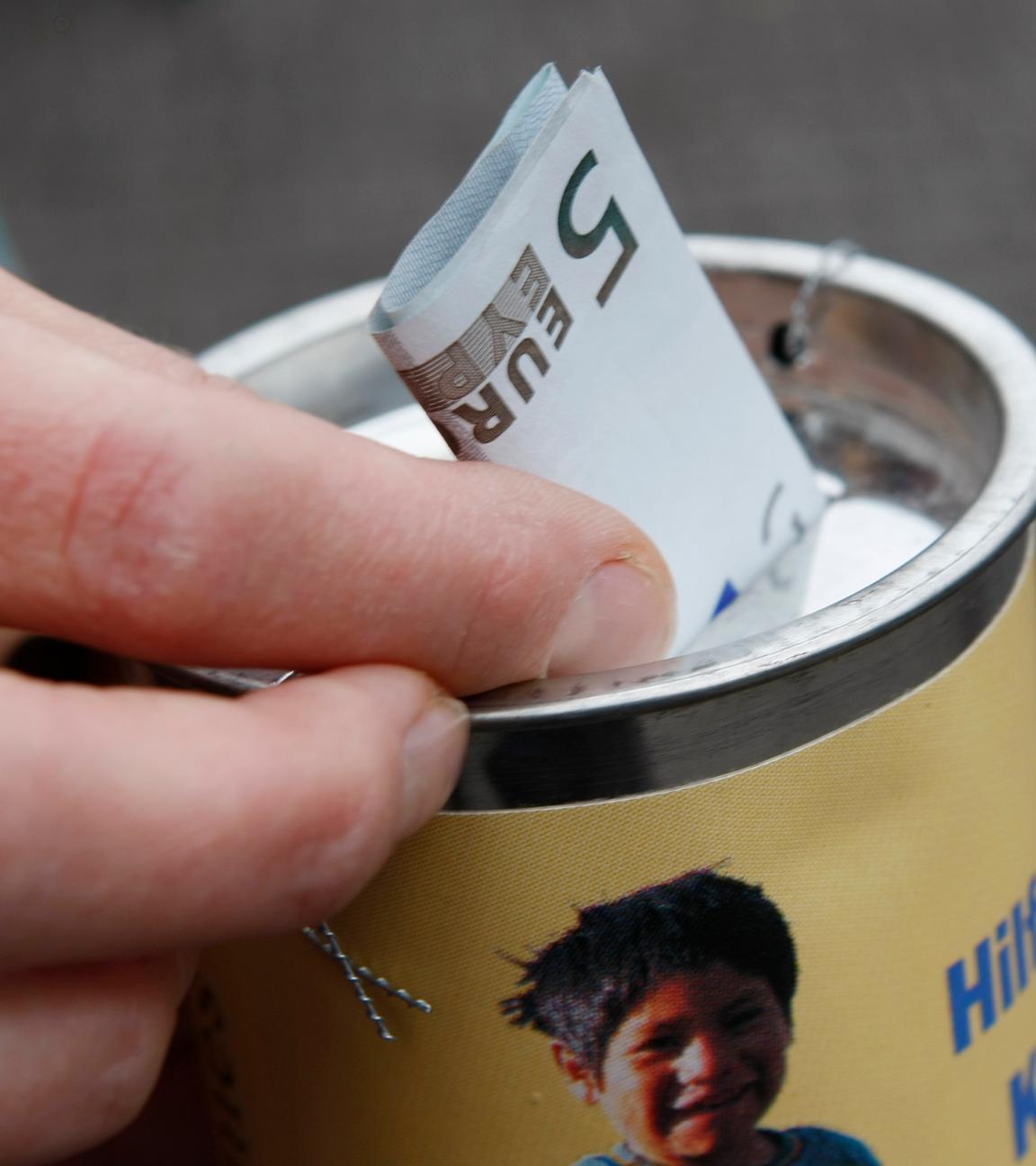 Symbolbild: Eine Passantin steckt am Donnerstag, 4.12. 2008, in Stuttgart einen Geldschein in die Sammelbüchse eines Kinderhilfswerks
