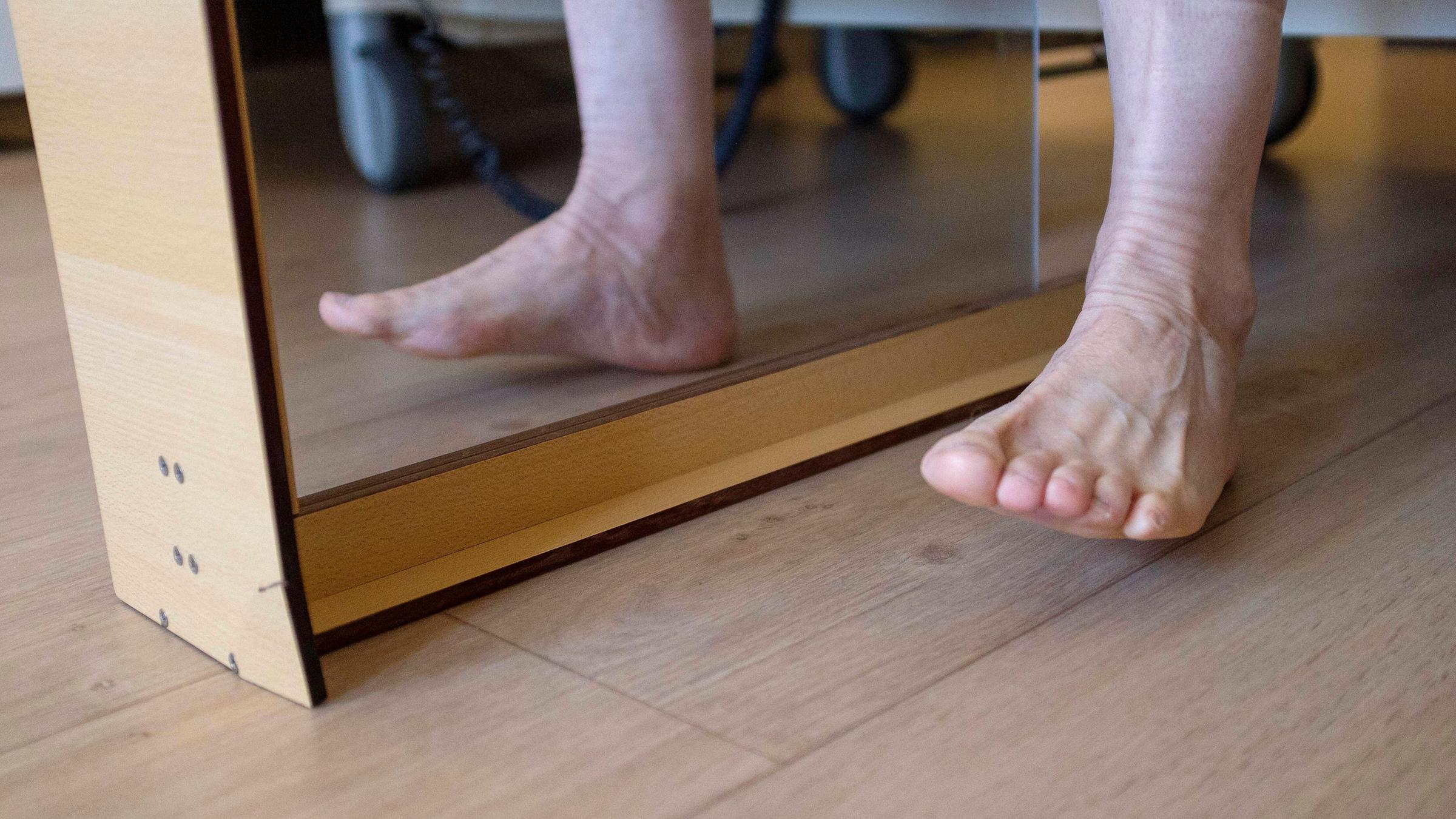 Mit dem Fuß wird eine Spiegeltherapie durchgeführt.