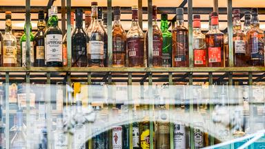 Berlin: Flaschen mit verschieden Sorten Alkohol sind hinter Fensterscheiben einer Bar zu sehen.