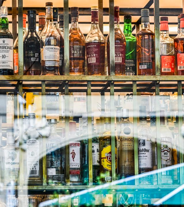 Berlin: Flaschen mit verschieden Sorten Alkohol sind hinter Fensterscheiben einer Bar zu sehen.
