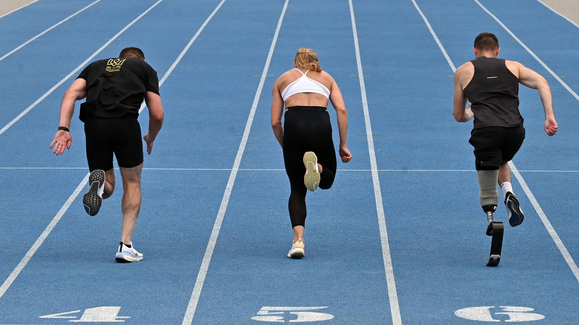 Es sind drei Sprinter von hinten zu sehen wie sie trainieren.