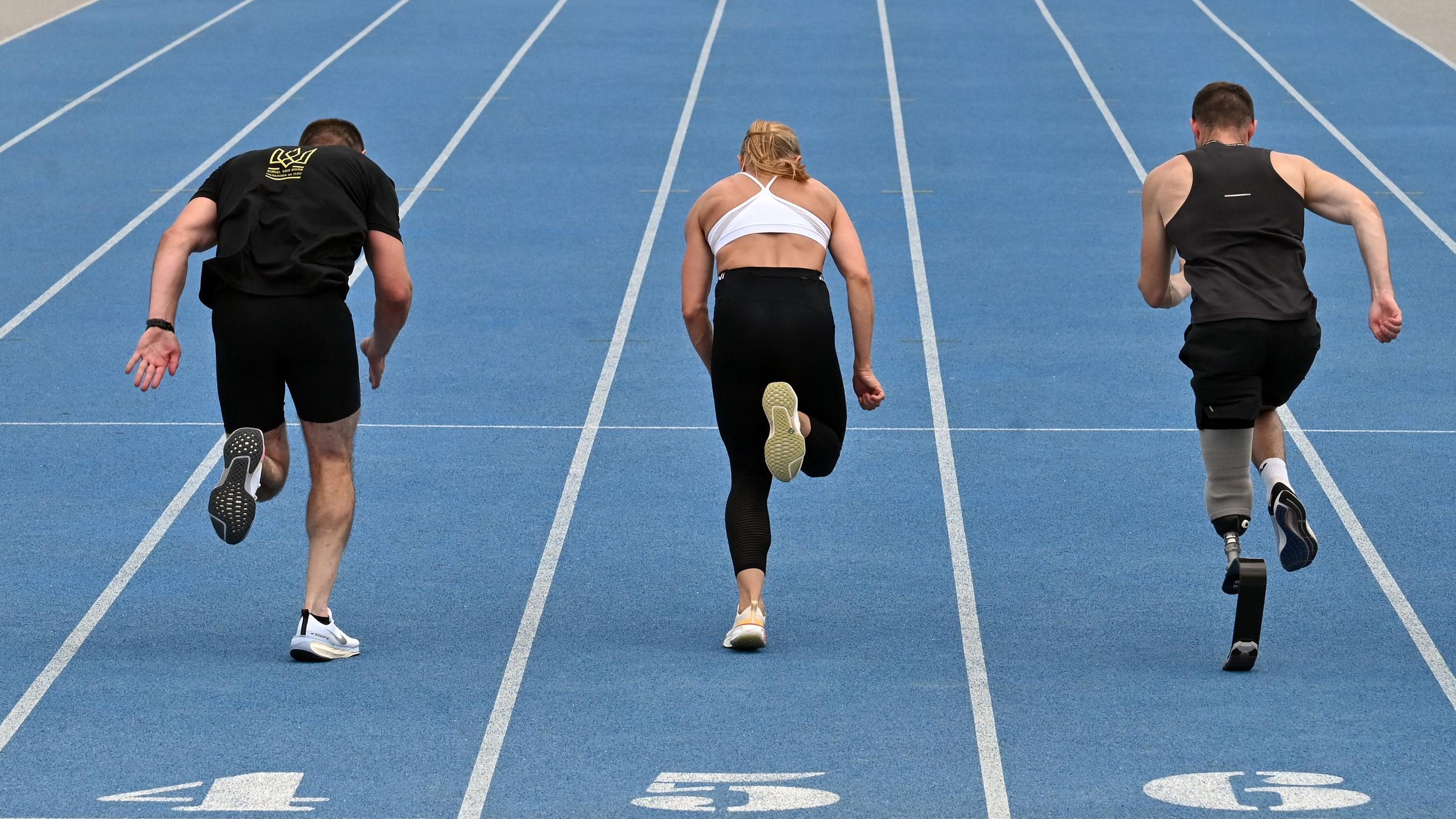 Es sind drei Sprinter von hinten zu sehen wie sie trainieren.