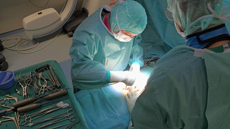 Zwei Chirugen operieren in einem OP-Saal an einer Wirbelsäule.