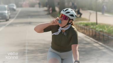 Frau fährt Rennrad und nutzt ein Asthmaspray.