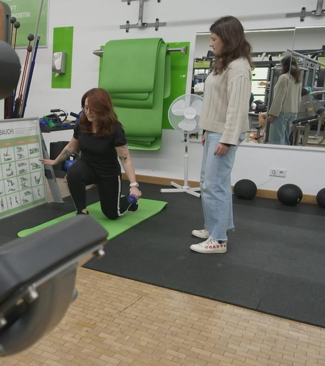 Frau macht Dehnübungen, eine andere Frau schaut ihr zu.