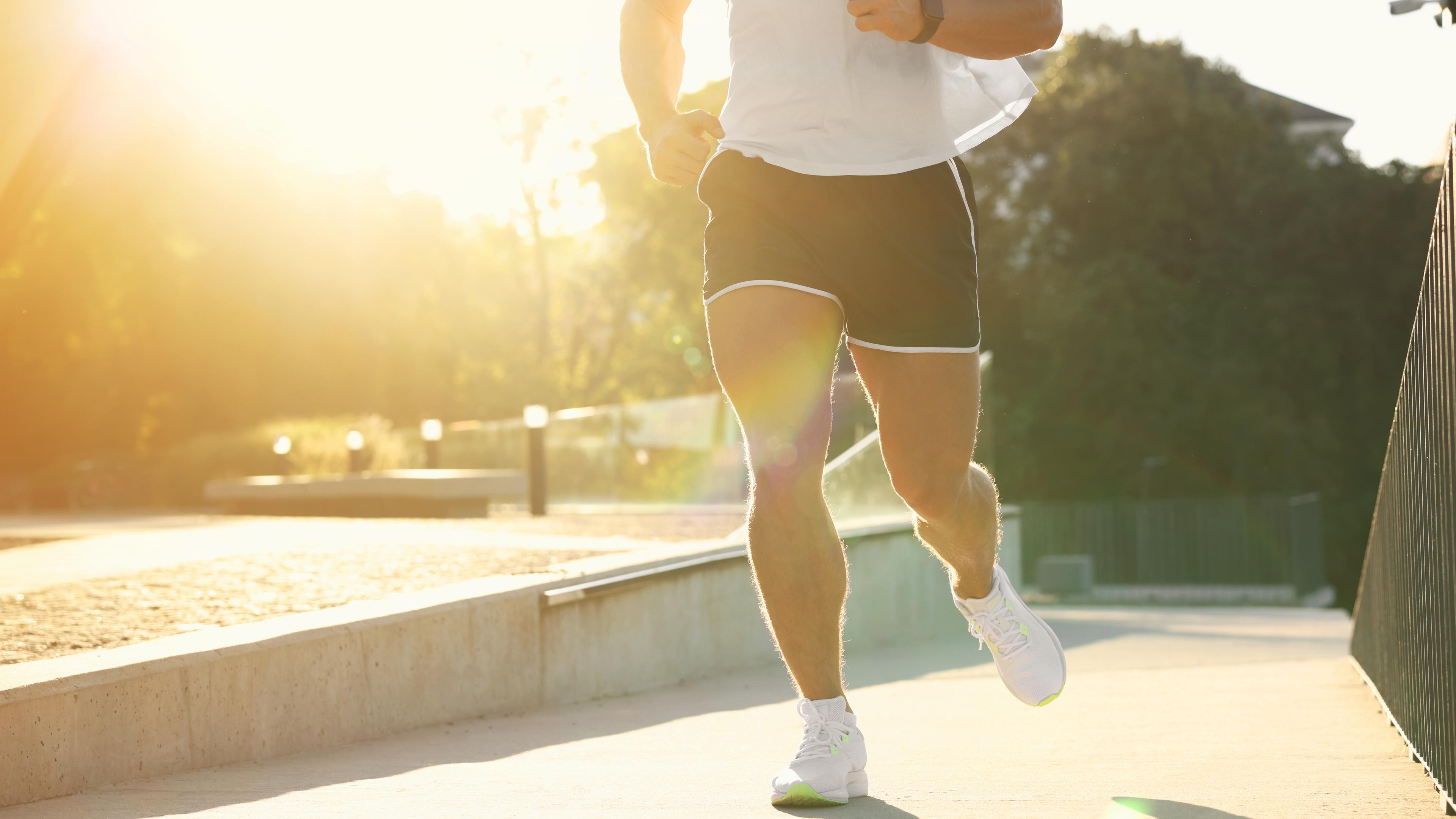 Torso eines Mannes, der in der sommerlichen Morgensonne joggt.