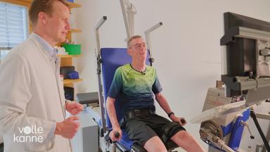 Mann macht unter Aufsicht einen Arztes Sport an einem Fitnessgerät