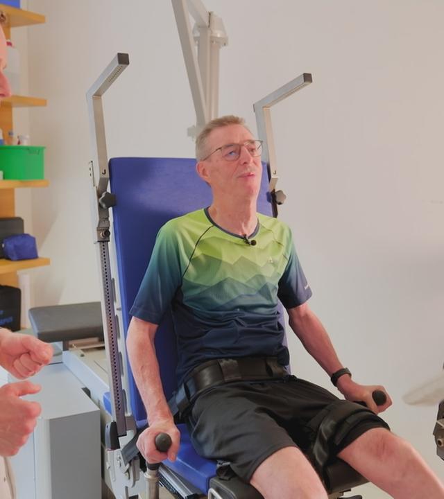 Mann macht unter Aufsicht einen Arztes Sport an einem Fitnessgerät