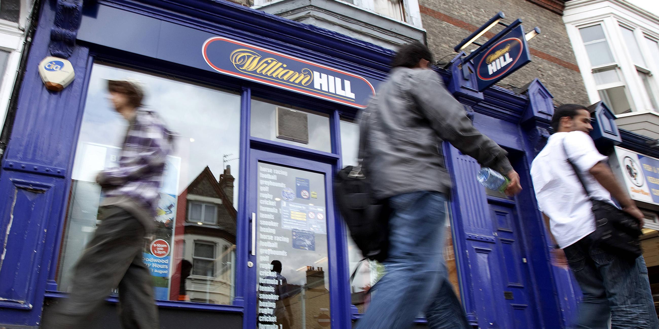 Archiv: Menschen gehen vor einer Filiale von dem Sportwettanbieter William Hill ,in Großbritannien, vorbei.