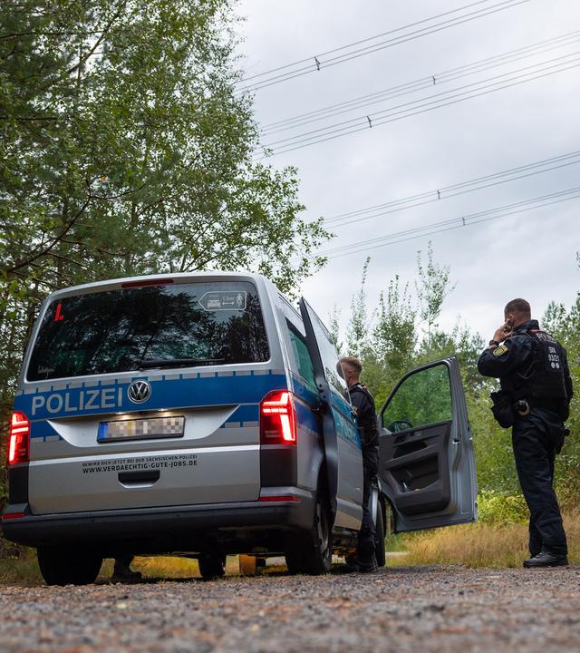 Polizeikräfte stehen in einem Waldstück unter einer Stromtrasse nahe dem Ort Schleife im Landkreis Görlitz, Sachsen, am 04.09.2026.