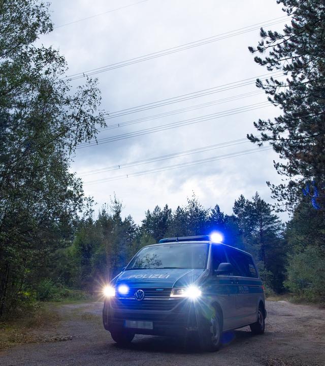 Polizeikräfte stehen in einem Waldstück unter einer Stromtrasse nahe dem Ort Schleife im Landkreis Görlitz, Sachsen, am 04.09.2026.