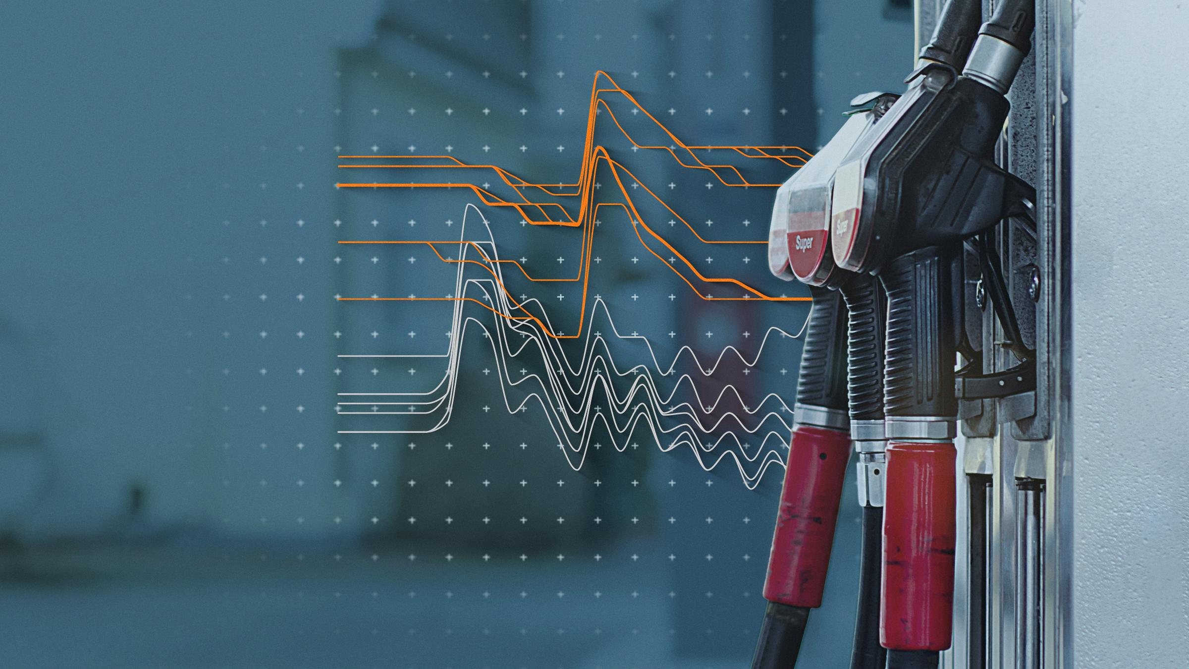 Zapfsäulen einer Tankstelle, dahinter eine Grafik zum Verlauf der Tankpreise