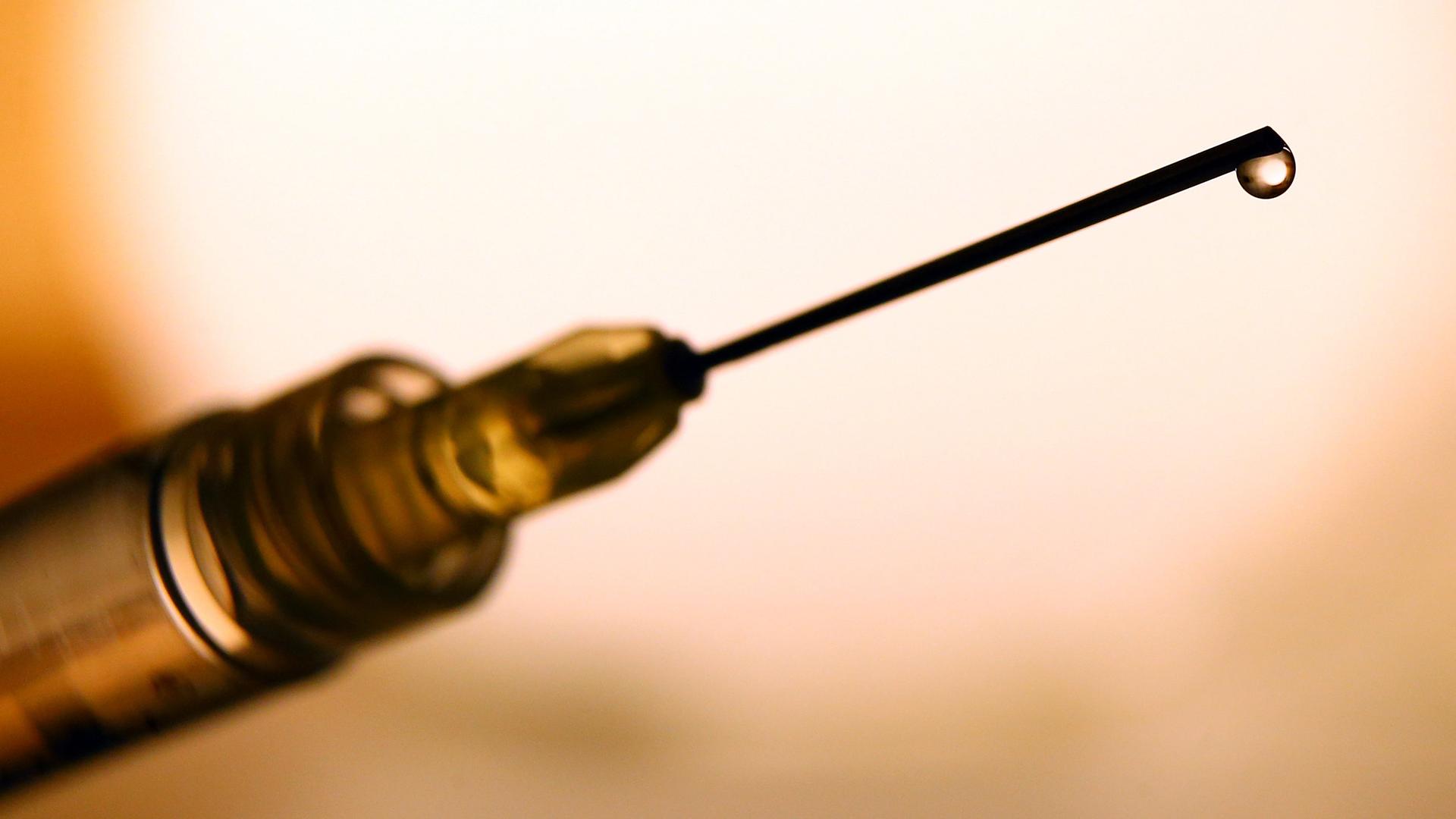 Eine Flüssigkeit tropft aus der Kanüle einer Spritze