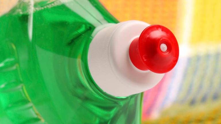 Nahaufnahme einer Spülmittelflasche vor einem Wischtuch.