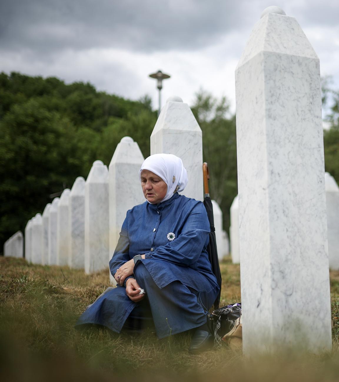Eine bosnische Muslimin trauert neben dem Grab ihres Verwandten, eines der Opfer des Völkermords von Srebrenica.