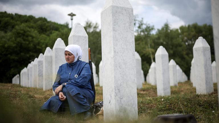 Eine bosnische Muslimin trauert neben dem Grab ihres Verwandten, eines der Opfer des Völkermords von Srebrenica.