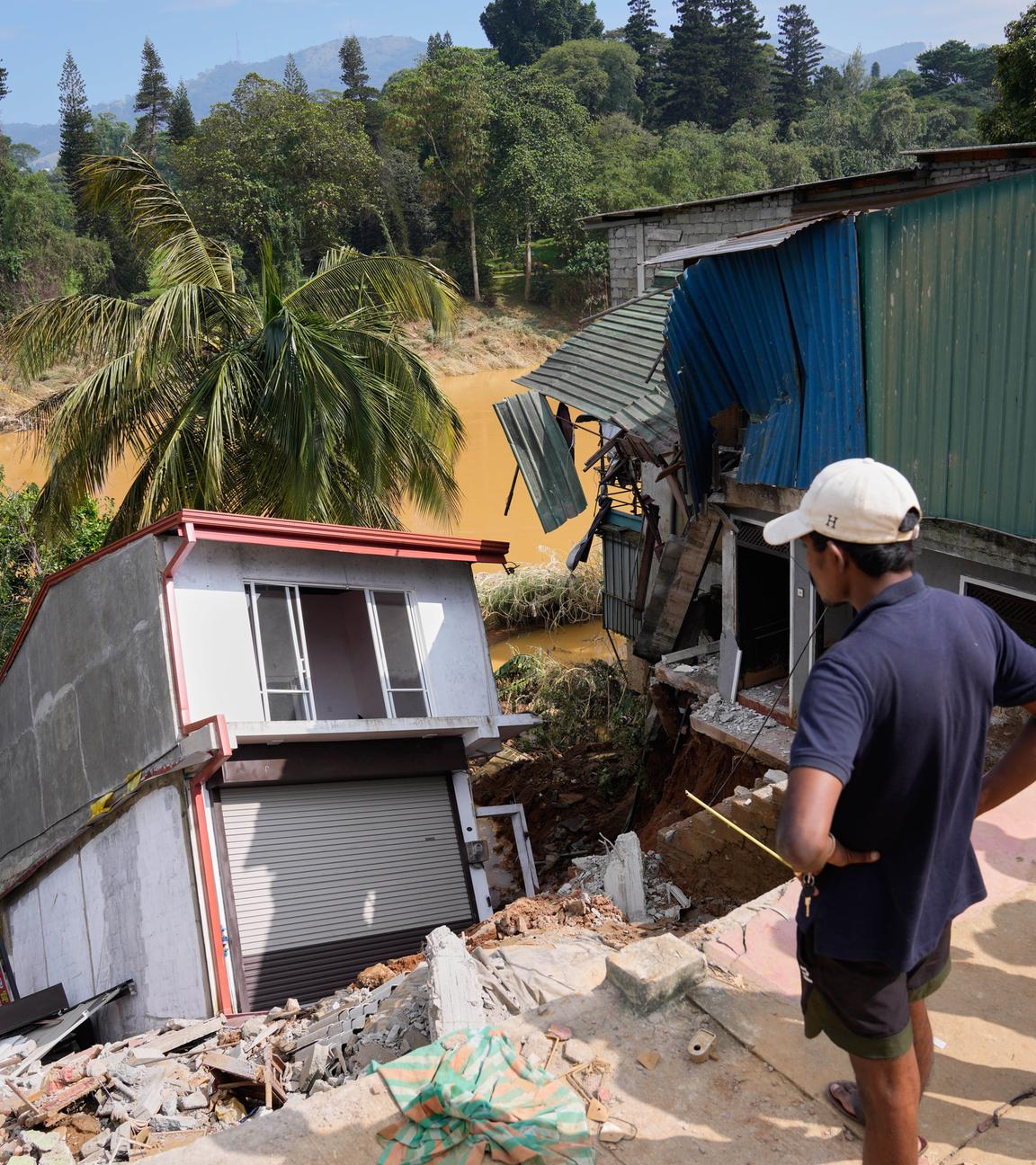 Menschen stehen vor einem beschädigten Gebäude nach einer Flut in Peradeniya in Sri Lanka.