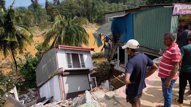 Menschen stehen vor einem beschädigten Gebäude nach einer Flut in Peradeniya in Sri Lanka.