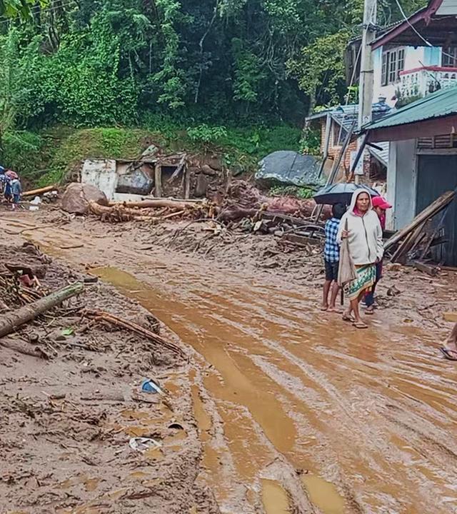 Menschen gehen in Nawalapitiya, Sri Lanka, nach starken Regenfällen über eine schlammbedeckte Straße.
