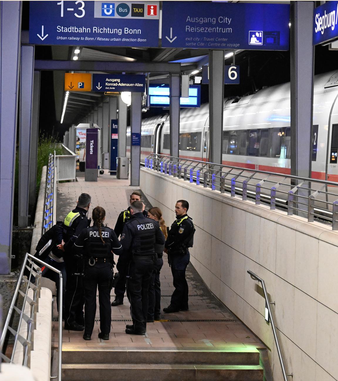 03.04.2026, Nordrhein-Westfalen, Siegburg: Polizisten stehen auf einem Bahnsteig im Bahnhof Siegburg, auf dem ein ICE der Deutschen Bahn steht.