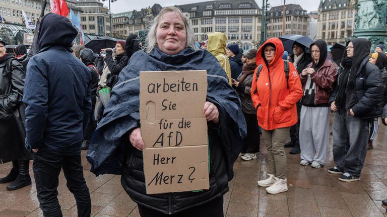 Eine Frau hält auf der Demonstration unter dem Motto «Wir sind das Stadtbild» ein Schild mit der Aufschrift «Arbeiten Sie für die AfD Herr Merz?».