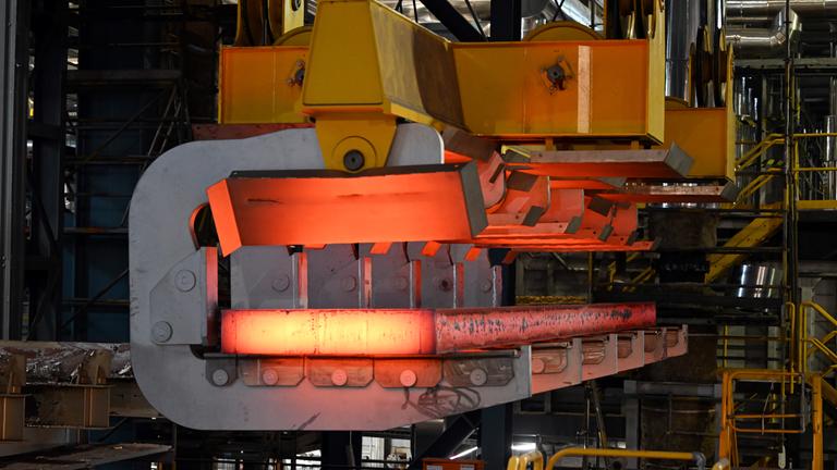 Eine glühende Bramme wird mit einem Kran aus der Stranggießanlage bei Thyssenkrupp Steel transportiert. 
