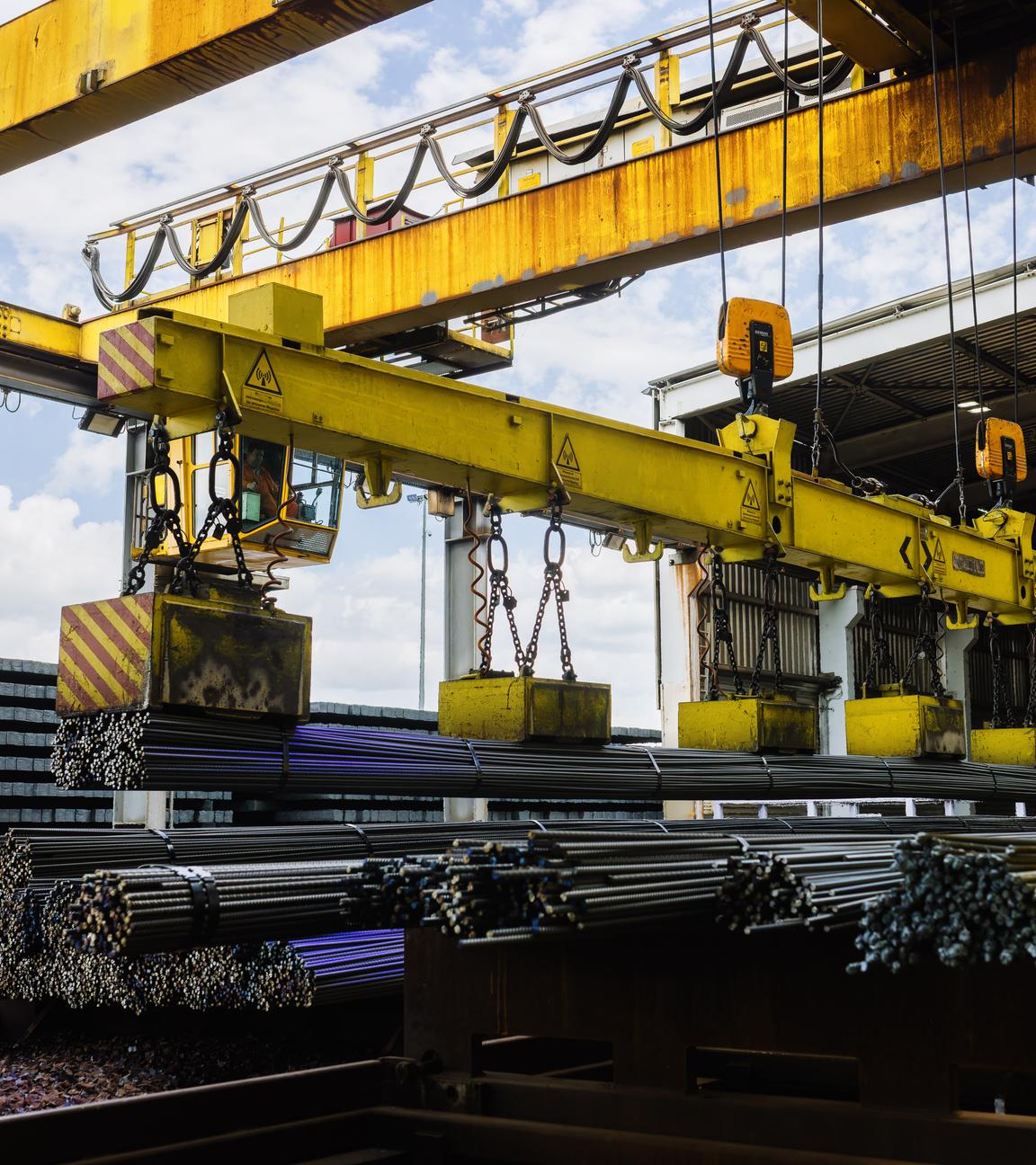 Ein Kran tranportiert frisch gewalzten Armierungsstahl