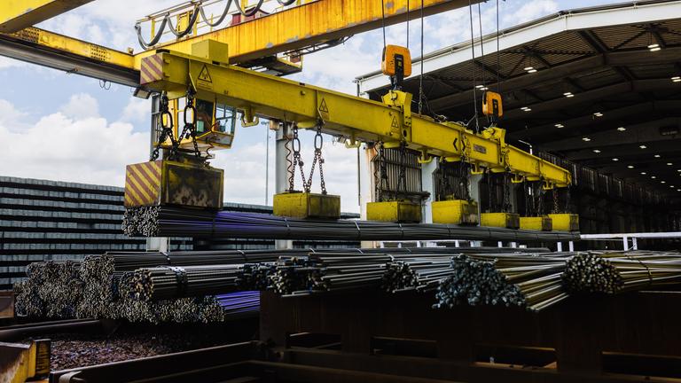 Ein Kran tranportiert frisch gewalzten Armierungsstahl