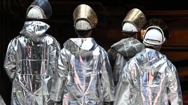 Symbolbild: Stahlarbeiter stehen vor einem Hochofen. 