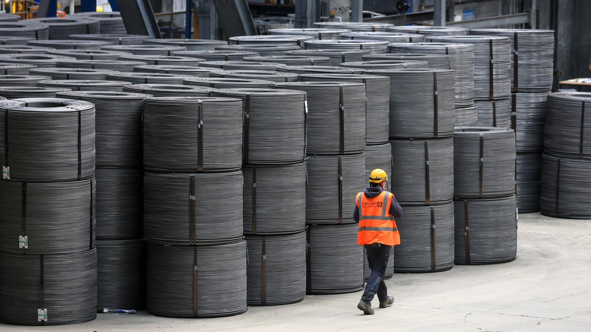 Sachsen, Riesa: Ein Mitarbeiter geht an Drahtrollen in den Elbe-Stahlwerken Feralpi vorbei.