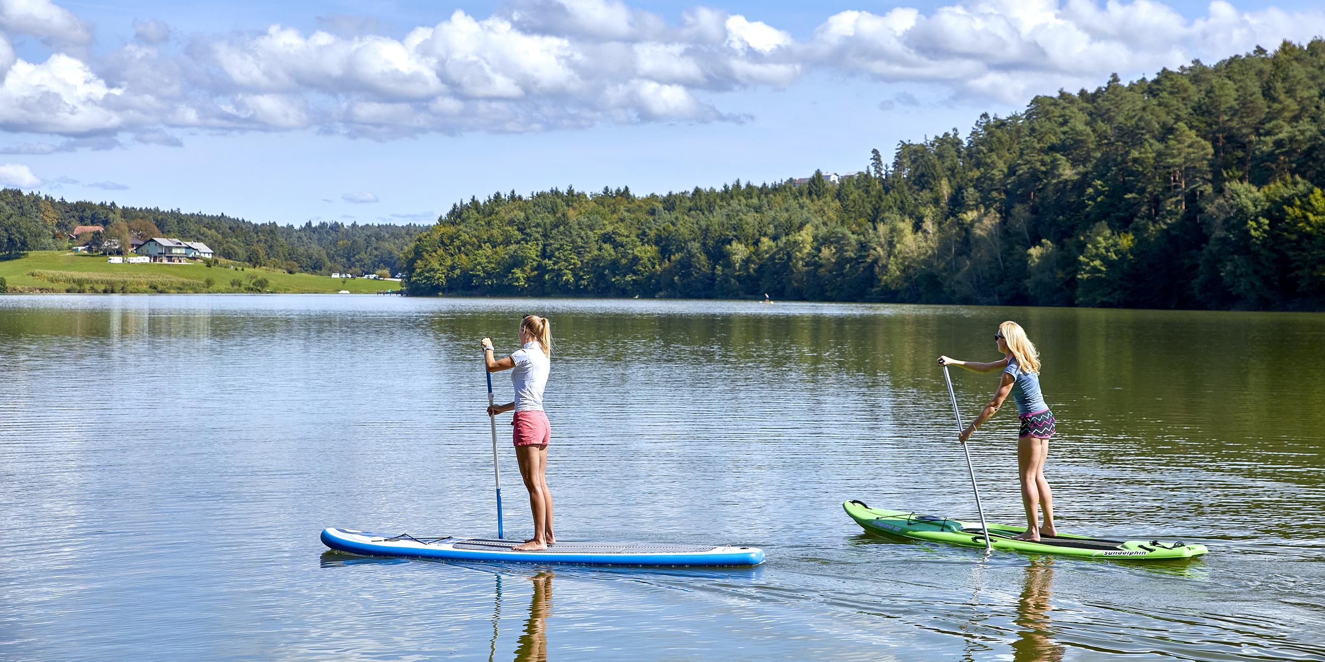 Zwei Frauen beim Stand Up Paddling auf einem See