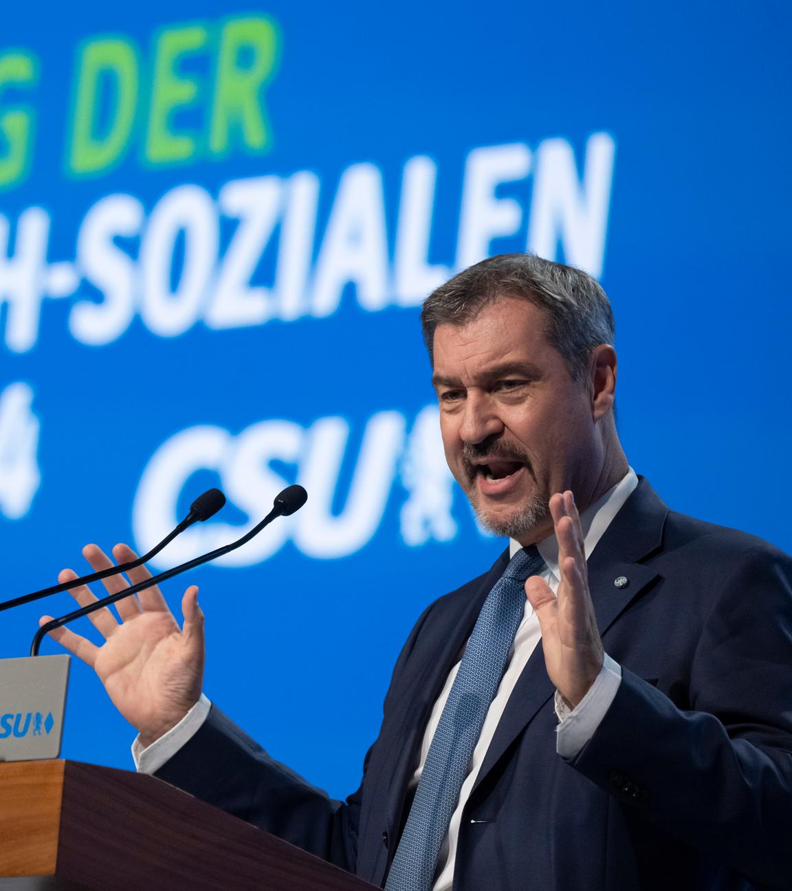 Germany's Christian Democratic Union (CDU) leader Friedrich Merz (2nd L) listens as Bavaria's State Premier and leader of the conservative Christian Social Union (CSU) party Markus Soeder (R) speaks to greet delegates of the CSU party congress in Augsburg, southern Germany, on October 12, 2024. (Photo by Michaela STACHE / AFP)