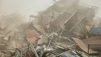 Menschen untersuchen am 28. März 2025 nach einem Erdbeben die Trümmer eines eingestürzten Gebäudes in Mandalay.
