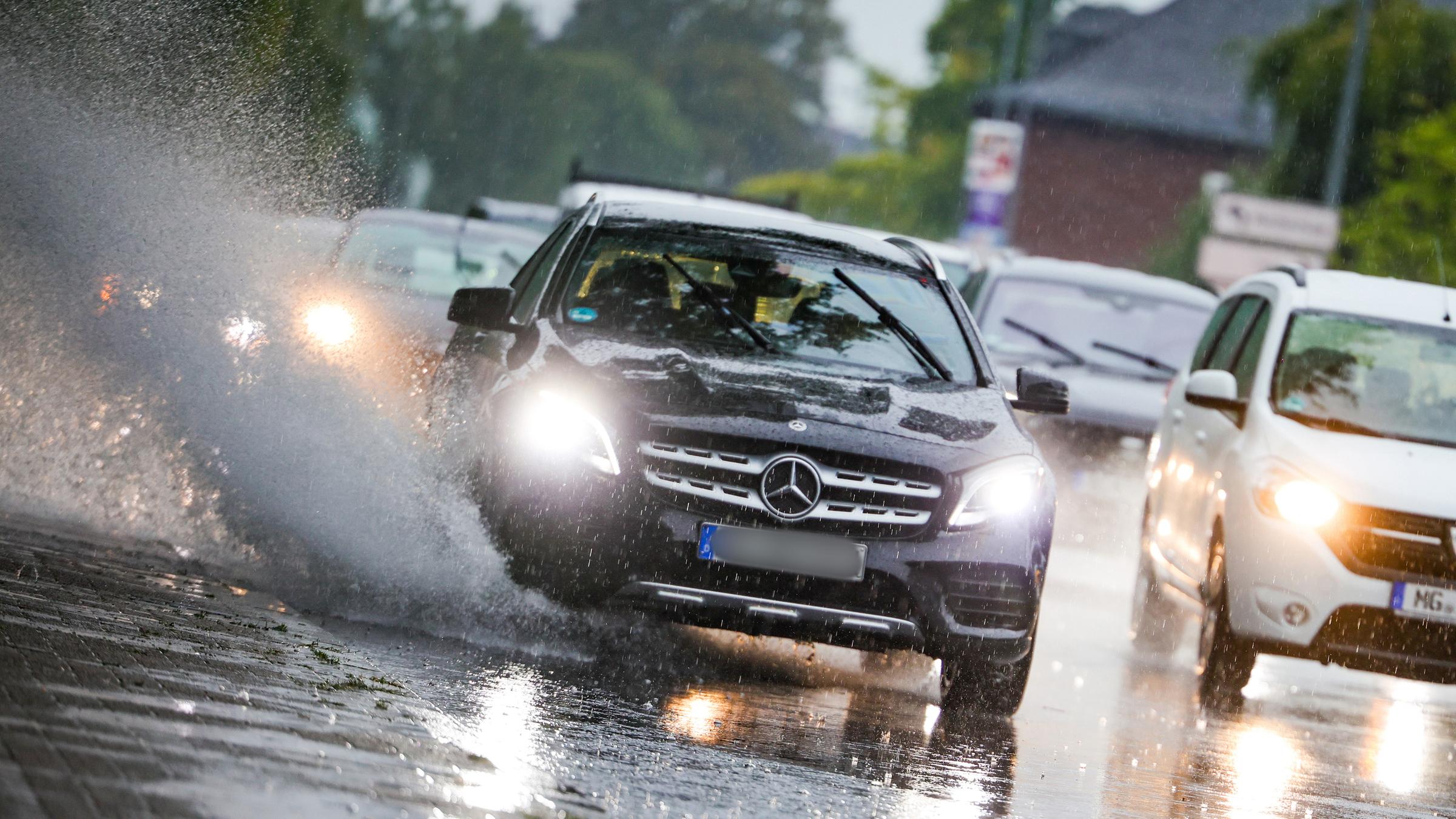 Autos fahren bei Regen mit eingeschalteten Scheinwerfern über nasse Straßen, auf denen sich große Pfützen gebildet haben, aufgenommen am 09.09.2025