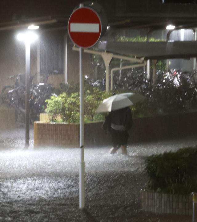 n Fußgänger geht auf einer überfluteten Straße in der Stadt Chiba nahe Tokio, nachdem sintflutartige Regenfälle über Ostjapan niedergegangen waren.