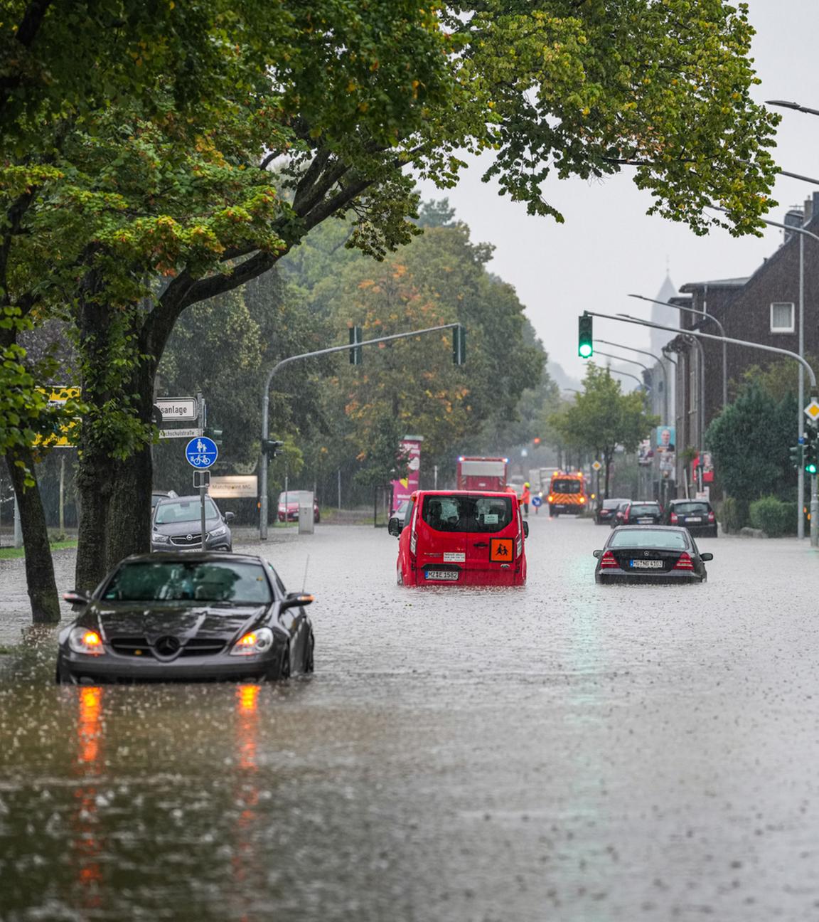 Nordrhein-Westfalen, Mönchengladbach: Autos fahren bei starkem Regen durch eine überflutete Straße.