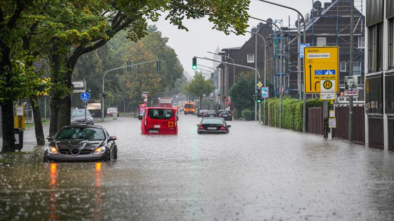 Nordrhein-Westfalen, Mönchengladbach: Autos fahren bei starkem Regen durch eine überflutete Straße.