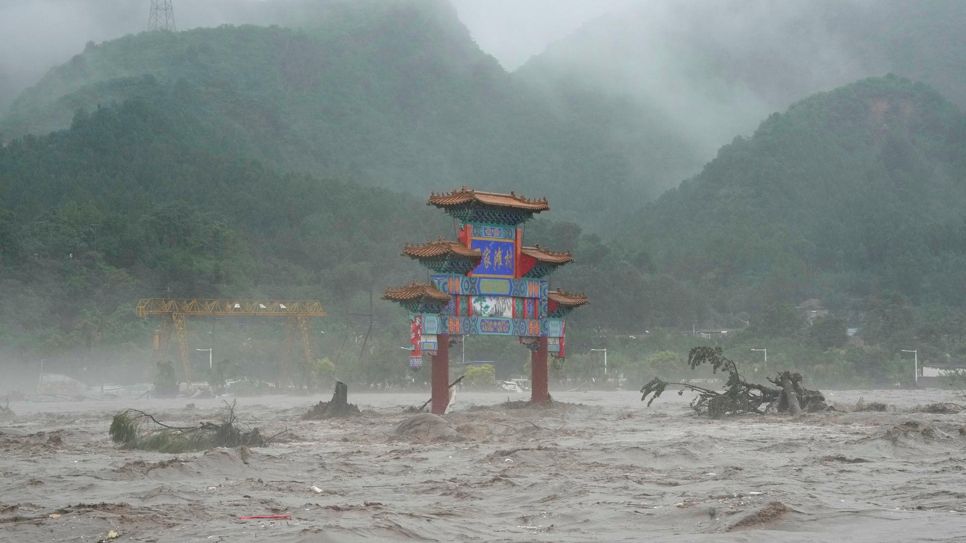 China, Peking: Ein traditionelles Tor wird am 1. August 2023 von Hochwasser umgeben.