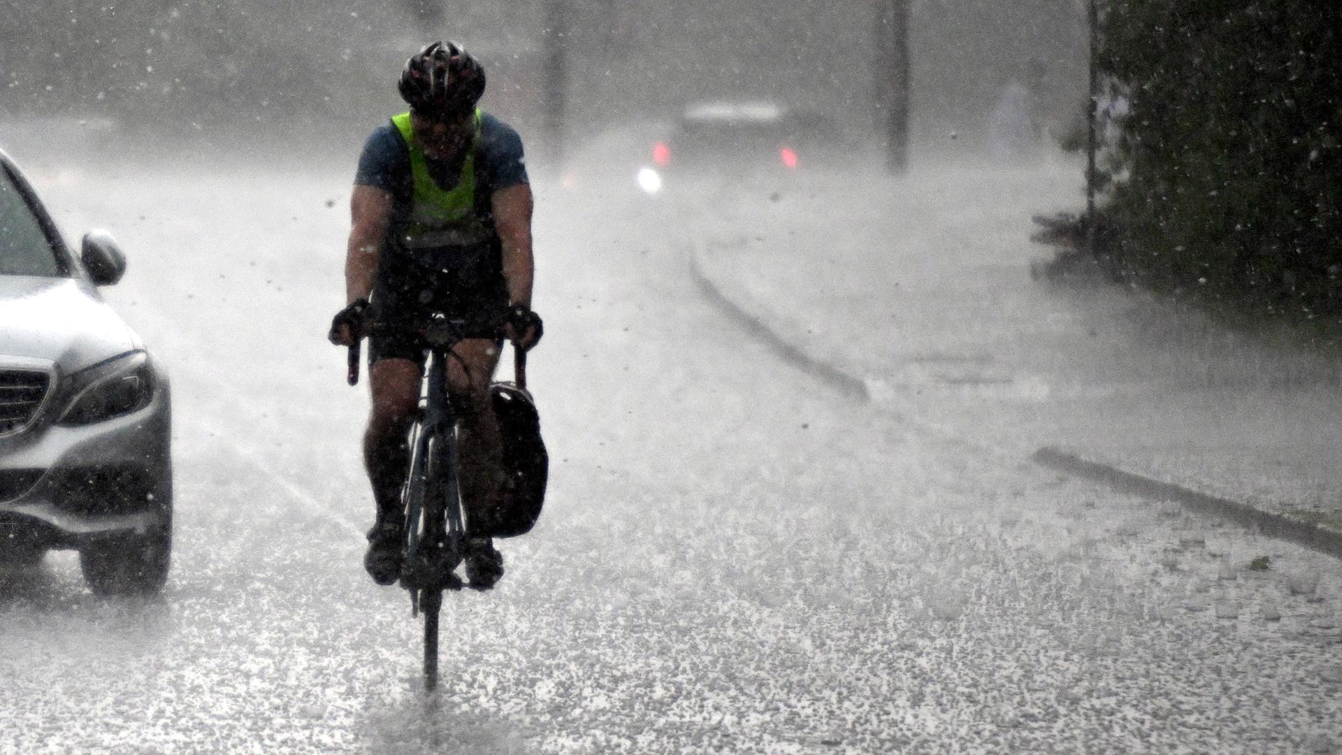 Ein Radfahrer fährt durch einen heftigen Regenschauer. 