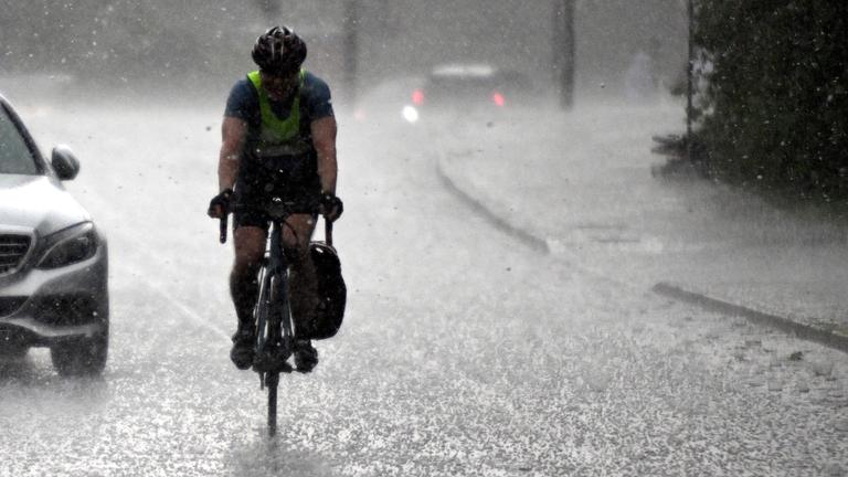 Ein Radfahrer fährt durch einen heftigen Regenschauer. 
